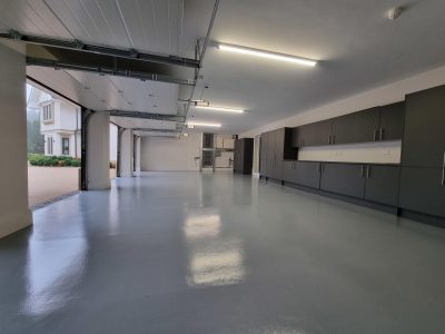 a large garage featuring dark grey cupboards running along the back wall
