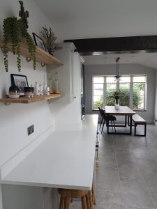 a white wall of a kitchen adorned with wooden shelves and home accessories rotated