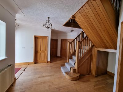 a wooden staircase leading to a hallway with white painted walls