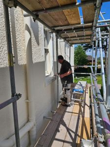 mc painters standing while on scaffolding outside a house